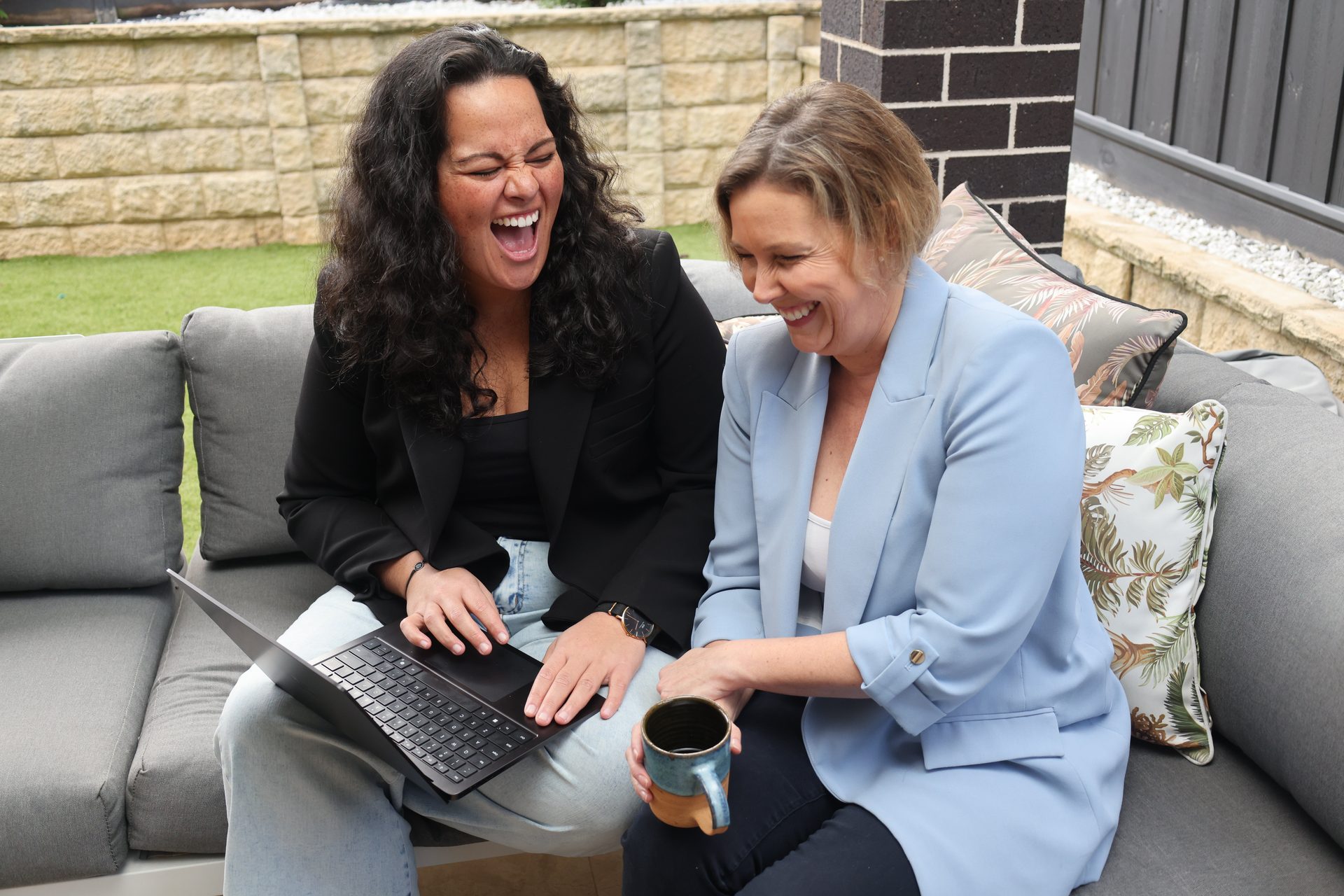 Christina and Sarah, Crewie co-founders, laughing together over a laptop